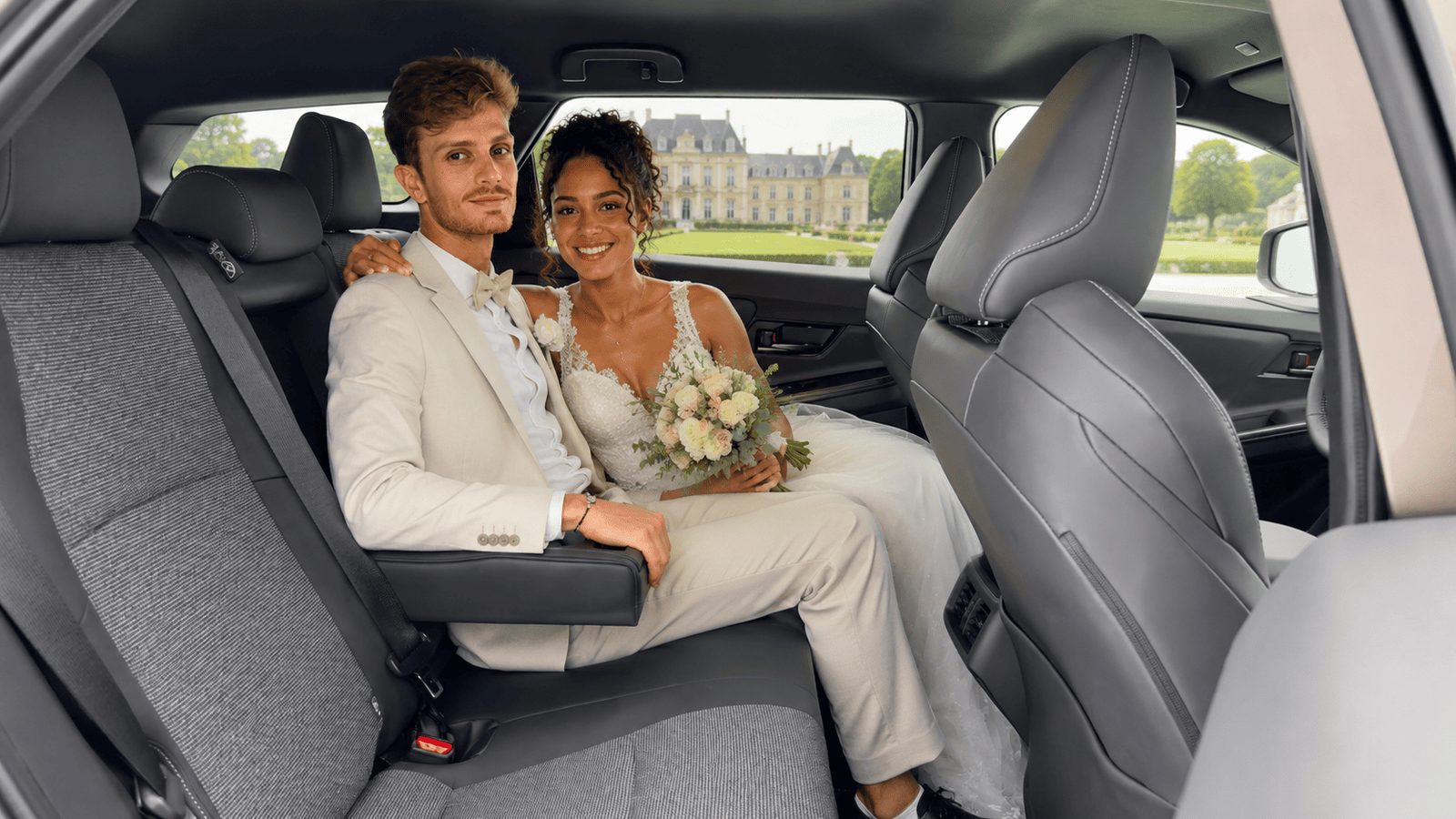 Mariés à l’arrière d’une voiture avec chauffeur devant un château — VTC mariage à Metz