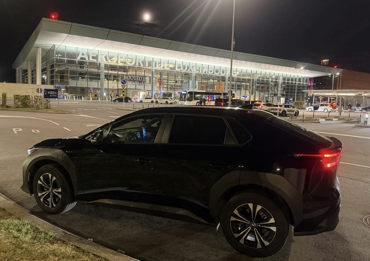 Le Toyota bZ4X noir de VTC G stationné devant le terminal de l’aéroport de Luxembourg-Findel, lors d’un transfert de nuit au départ de Metz